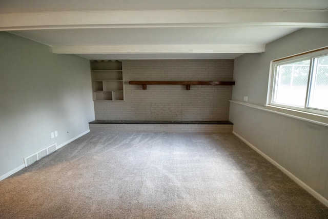 empty room featuring carpet flooring, beamed ceiling, and brick wall