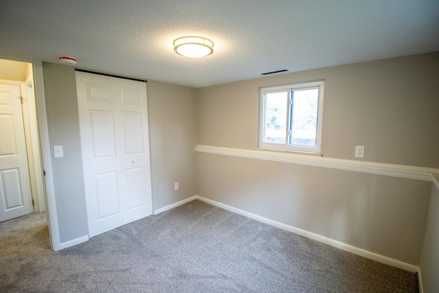 unfurnished bedroom with carpet flooring, a textured ceiling, and a closet