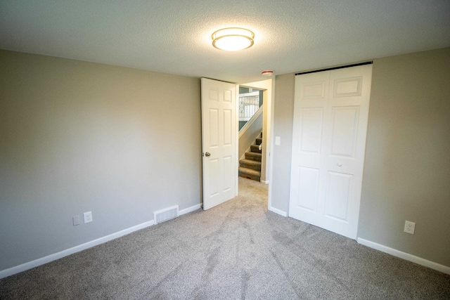 unfurnished bedroom with light carpet, a closet, and a textured ceiling