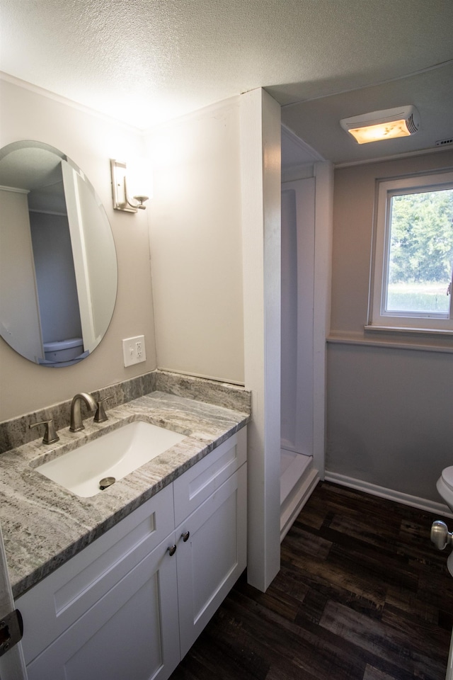 bathroom with walk in shower, a textured ceiling, vanity, hardwood / wood-style flooring, and toilet