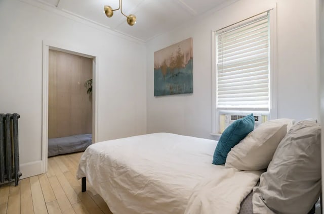 bedroom with radiator, crown molding, cooling unit, and light wood-type flooring