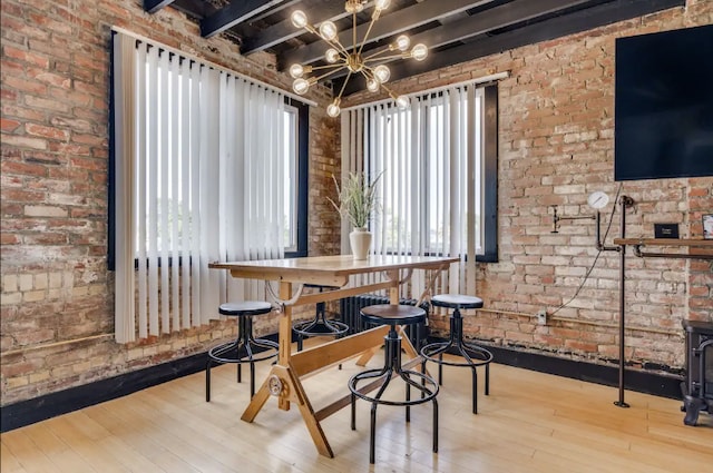 dining room with light wood-type flooring, brick wall, and an inviting chandelier