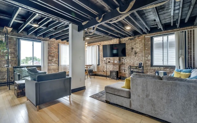 living room with light hardwood / wood-style floors, brick wall, and a brick fireplace