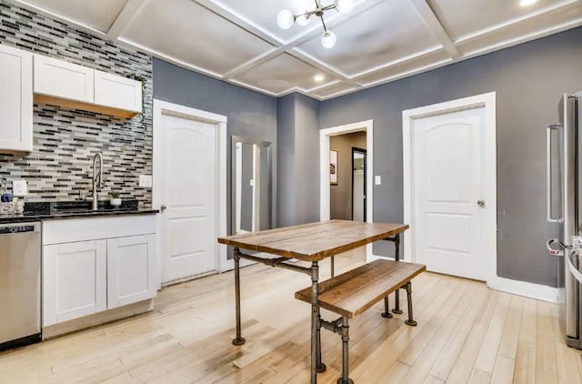 dining room featuring light wood-type flooring, coffered ceiling, and sink