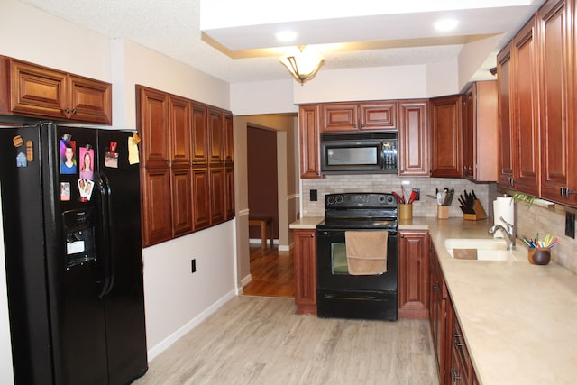 29352 Medburn Ct, Farmington Hills, MI 48336 - kitchen featuring tasteful backsplash, light countertops, light wood-style floors, black appliances, and a sink