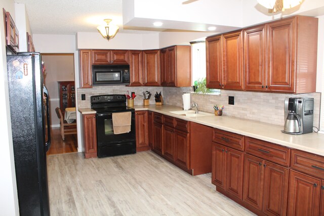 29352 Medburn Ct, Farmington Hills, MI 48336 - kitchen featuring light countertops, decorative backsplash, light wood-style flooring, black appliances, and a sink