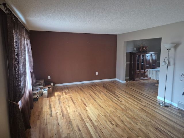 29352 Medburn Ct, Farmington Hills, MI 48336 - unfurnished living room featuring light wood finished floors, visible vents, a textured ceiling, and baseboards