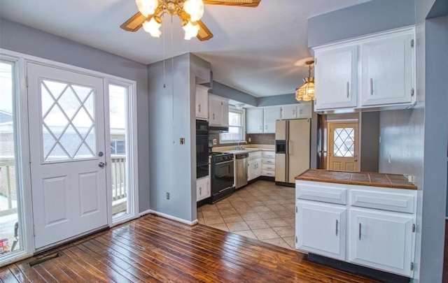 kitchen featuring a wealth of natural light, white cabinetry, tile counters, white fridge with ice dispenser, and light wood-type flooring