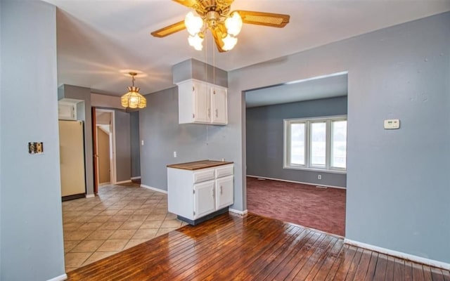 kitchen with ceiling fan, hanging light fixtures, white refrigerator, white cabinets, and light wood-type flooring