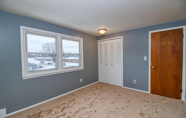 unfurnished bedroom with light colored carpet and a closet