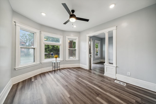 spare room with dark hardwood / wood-style flooring, a wealth of natural light, and decorative columns