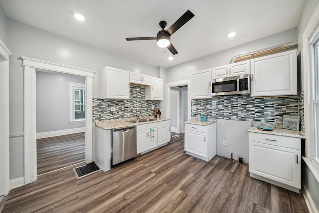 kitchen featuring dark hardwood / wood-style flooring, backsplash, stainless steel appliances, ceiling fan, and white cabinets