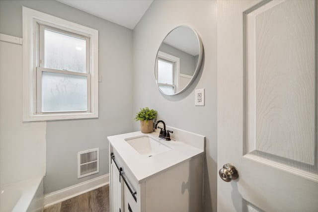 bathroom with hardwood / wood-style floors, vanity, and a washtub