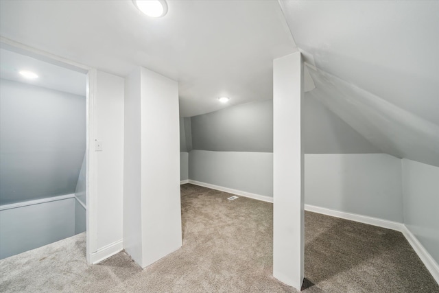 additional living space featuring light colored carpet and vaulted ceiling