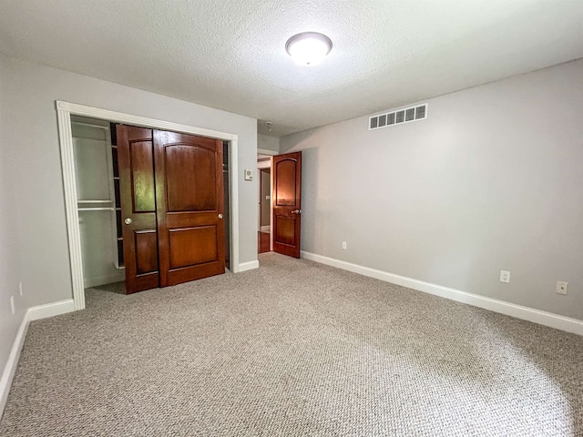 unfurnished bedroom with a textured ceiling, carpet floors, and a closet