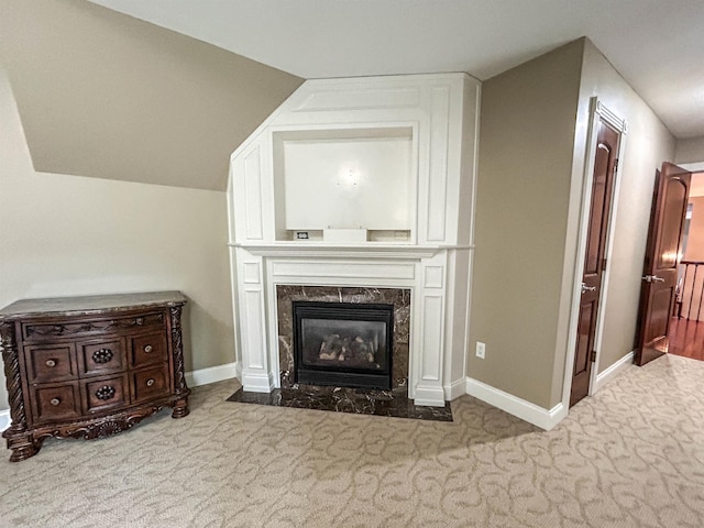 living room with light carpet, a high end fireplace, and vaulted ceiling