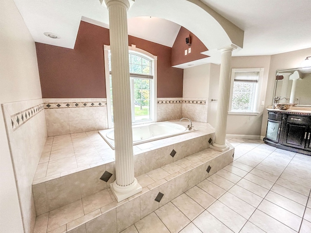 bathroom with tiled bath, ornate columns, tile patterned floors, and vanity