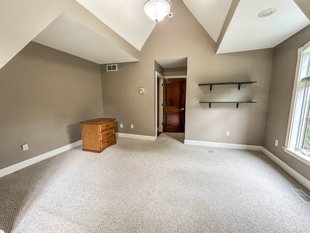 unfurnished living room featuring light colored carpet and vaulted ceiling