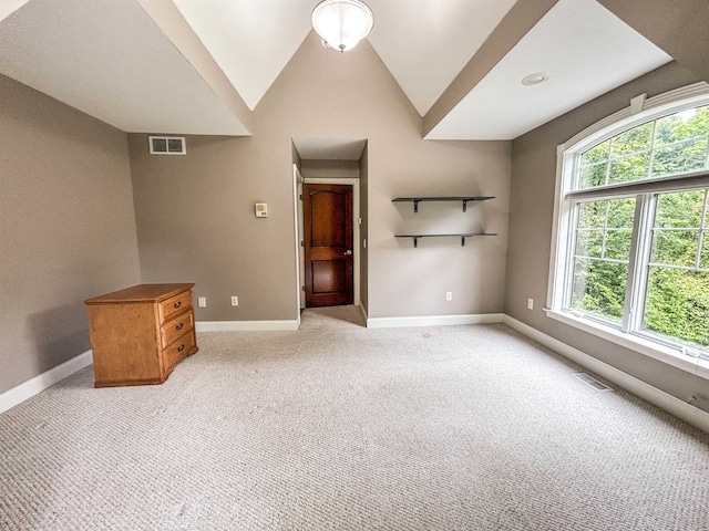 interior space with lofted ceiling, light carpet, and a wealth of natural light