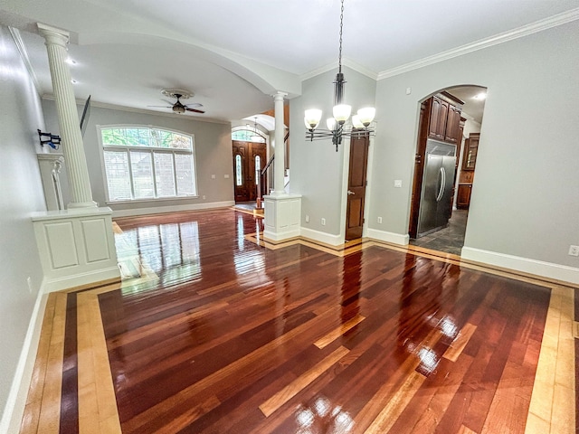 unfurnished dining area featuring ceiling fan with notable chandelier, crown molding, dark wood-type flooring, and ornate columns