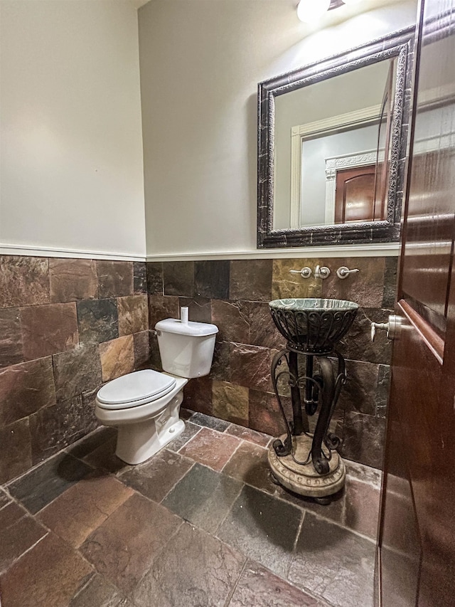 bathroom with toilet, tile walls, and sink