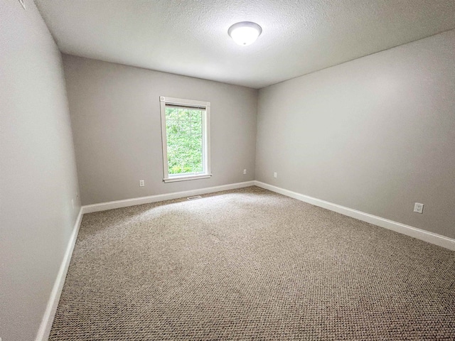 carpeted empty room featuring a textured ceiling