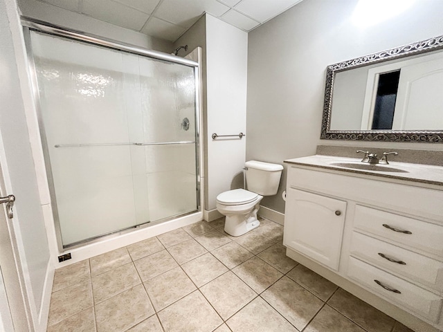 bathroom with tile patterned floors, an enclosed shower, toilet, a paneled ceiling, and vanity