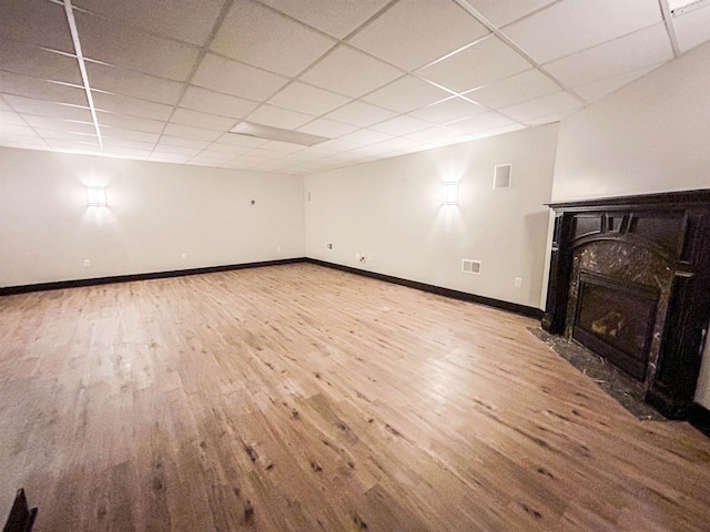 basement featuring a paneled ceiling, a premium fireplace, and hardwood / wood-style flooring