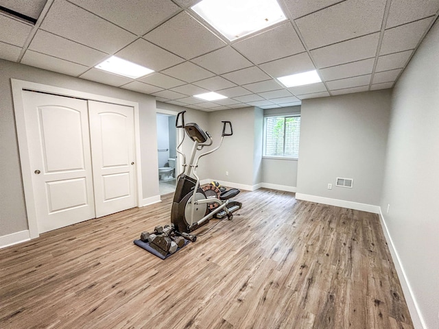 workout room with a paneled ceiling and light wood-type flooring