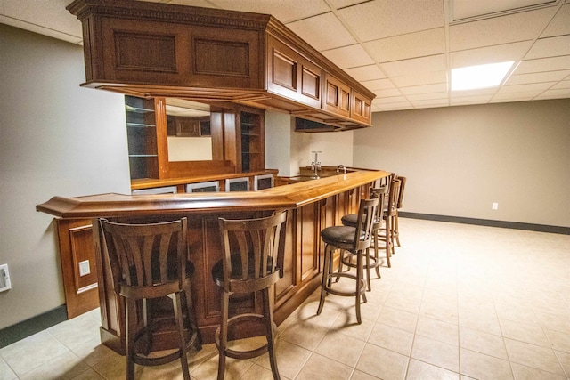 bar with a paneled ceiling and light tile patterned flooring