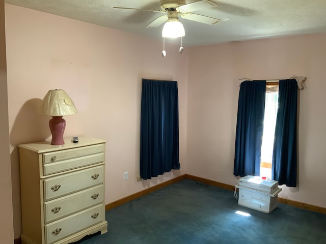 unfurnished bedroom with ceiling fan and dark carpet