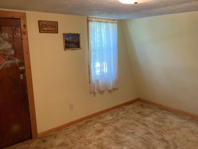 carpeted spare room with a textured ceiling