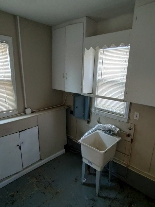 kitchen with white cabinets, concrete flooring, and sink