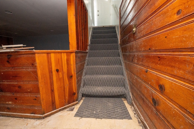 stairs featuring wood walls