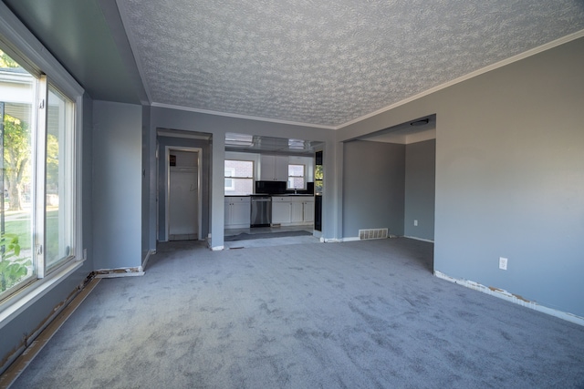 unfurnished living room featuring a wealth of natural light, light colored carpet, a textured ceiling, and ornamental molding