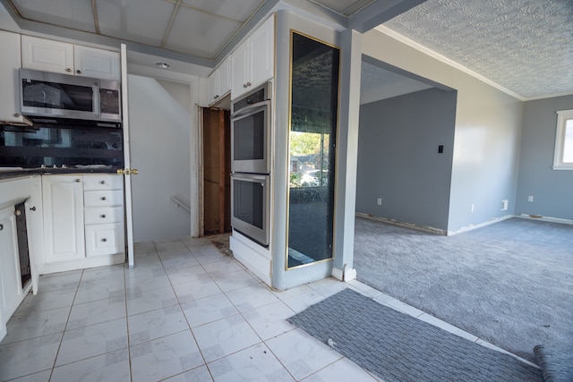 kitchen featuring white cabinetry, crown molding, light carpet, and appliances with stainless steel finishes