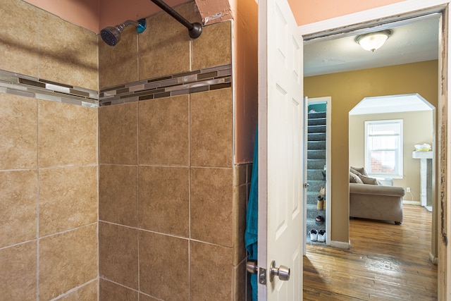 bathroom with a tile shower and hardwood / wood-style flooring