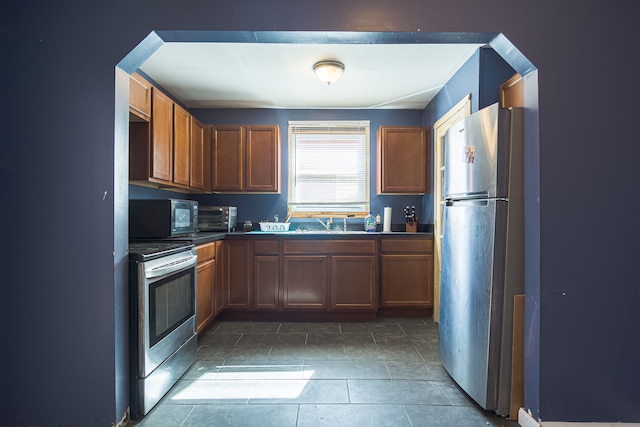 kitchen featuring sink, stainless steel appliances, and dark tile patterned flooring