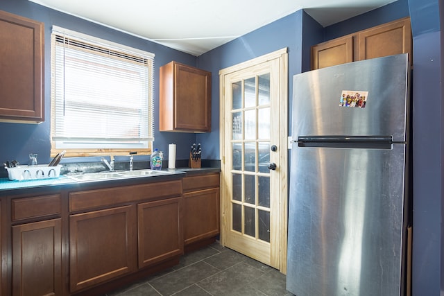 kitchen featuring stainless steel fridge, dark tile patterned flooring, and sink