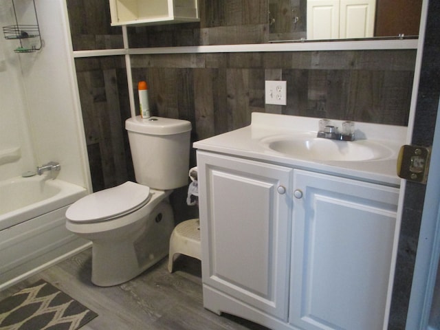 full bathroom featuring vanity, wood walls, toilet, wood-type flooring, and tub / shower combination