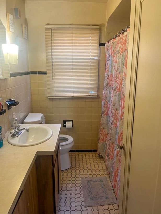 bathroom featuring vanity, toilet, and tile walls