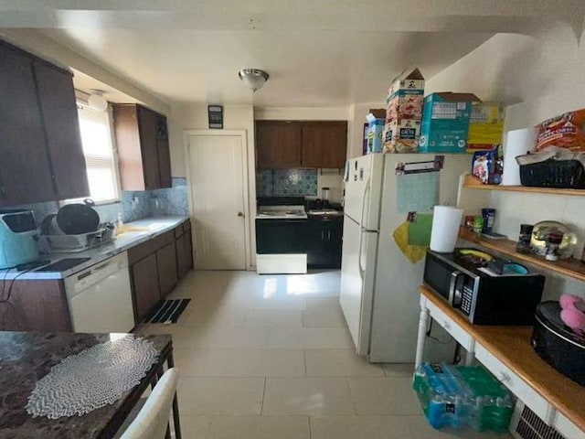 kitchen with backsplash, dark brown cabinets, white appliances, sink, and light tile patterned floors