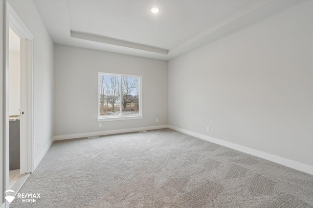 unfurnished room featuring a tray ceiling, carpet, recessed lighting, and baseboards