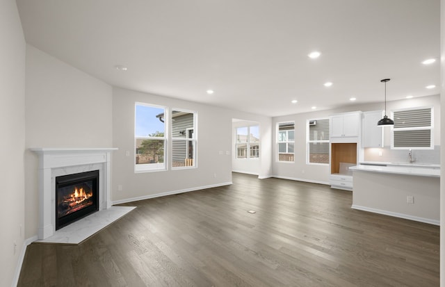 unfurnished living room featuring dark wood-type flooring, plenty of natural light, and a premium fireplace