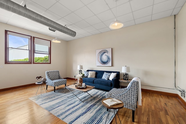 living room with hardwood / wood-style floors and a paneled ceiling