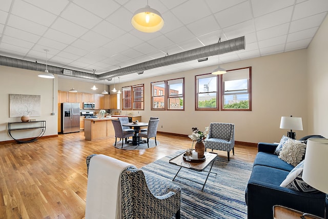 living room featuring light hardwood / wood-style flooring and a drop ceiling