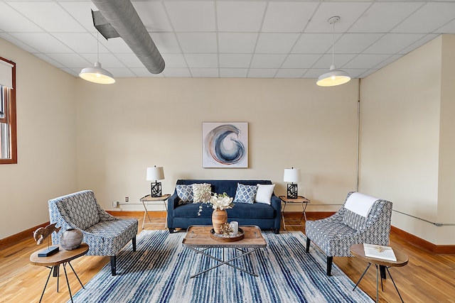 living room featuring wood-type flooring and a drop ceiling