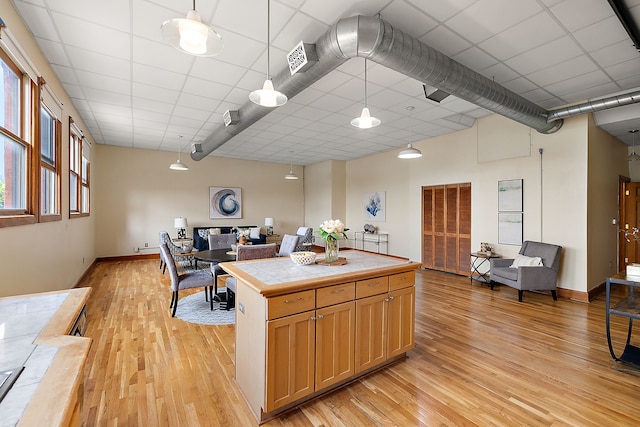 kitchen featuring pendant lighting, a paneled ceiling, tile countertops, and light hardwood / wood-style floors