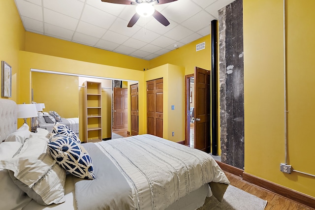 1395 Antietam Ave Unit 51, Detroit, MI 48207 - bedroom featuring wood finished floors, baseboards, a drop ceiling, ceiling fan, and a closet