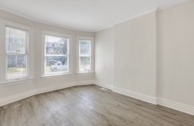 unfurnished room featuring hardwood / wood-style floors, a wealth of natural light, and ornamental molding